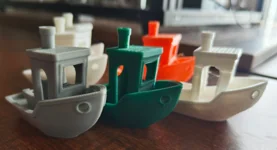 Small boat-shaped test parts in grey, green, orange and white