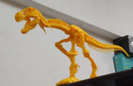 Yellow dinosaur skeleton model beside a printer